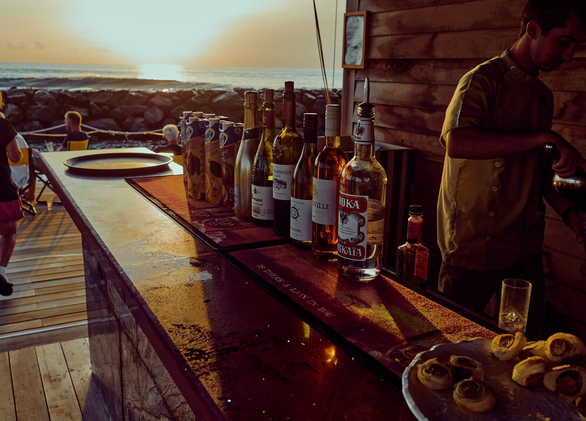 A beachfront bar at golden hour on Bãi Trường, with drinks set out and the sun low over the sea