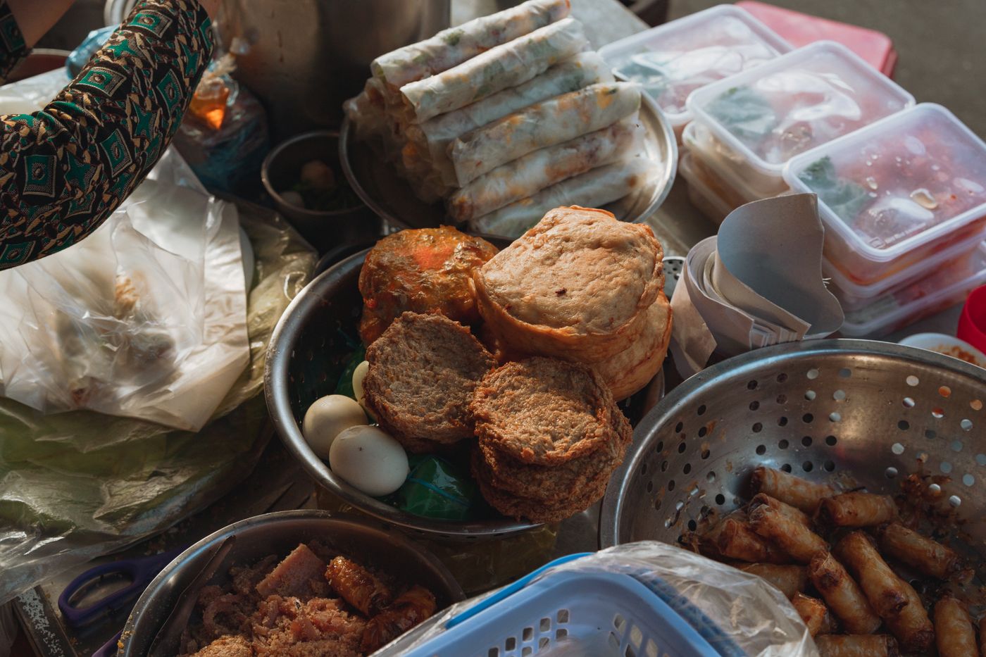 Fried fish cakes, fresh rolls and quail eggs laid out at a morning food stall, the kind you find inside Duong Dong market