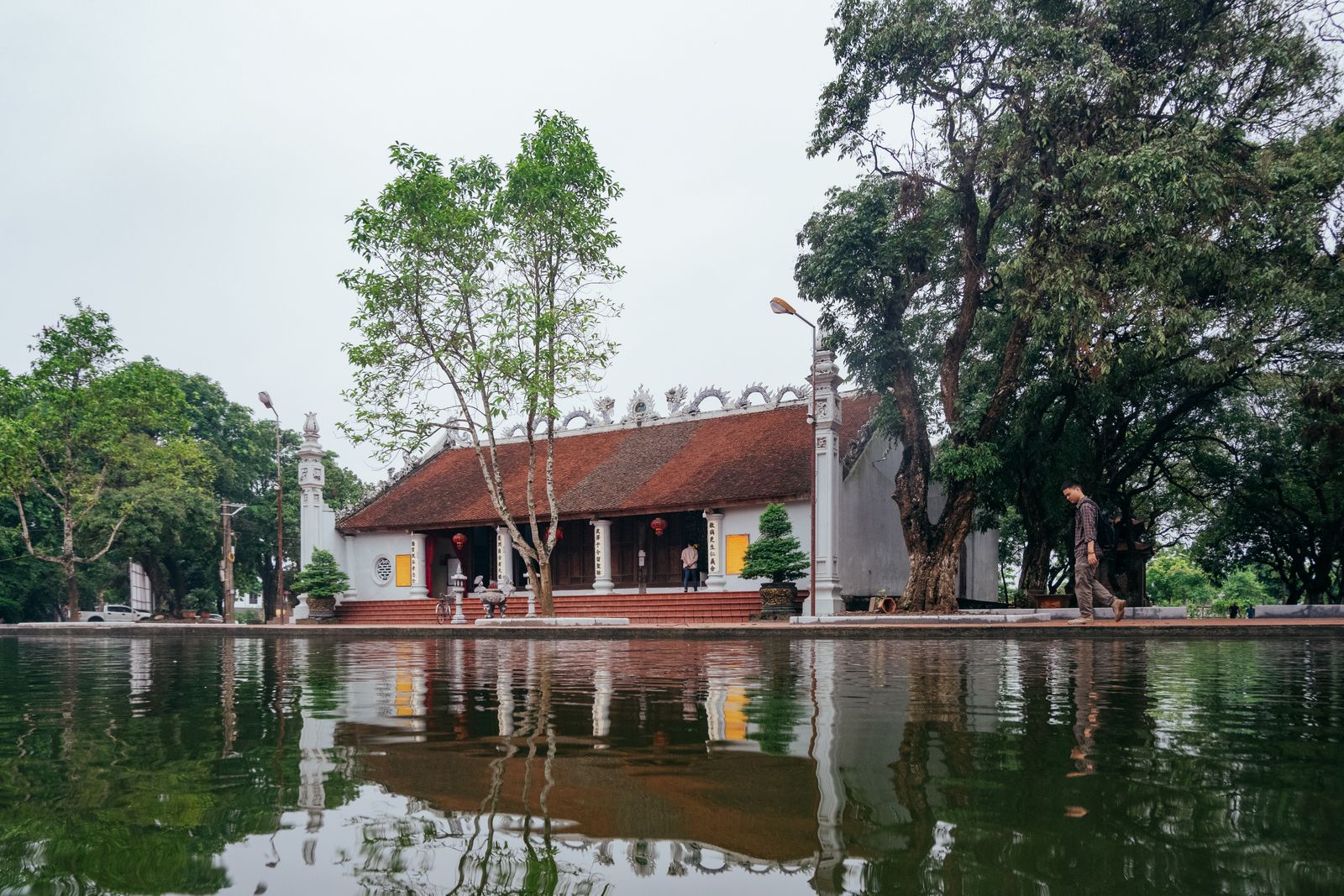 Traditional Vietnamese Buddhist temple reflected in a still pond, surrounded by old trees — the same meditative quiet waits at Thiền Viện Trúc Lâm Hộ Quốc, Phú Quốc