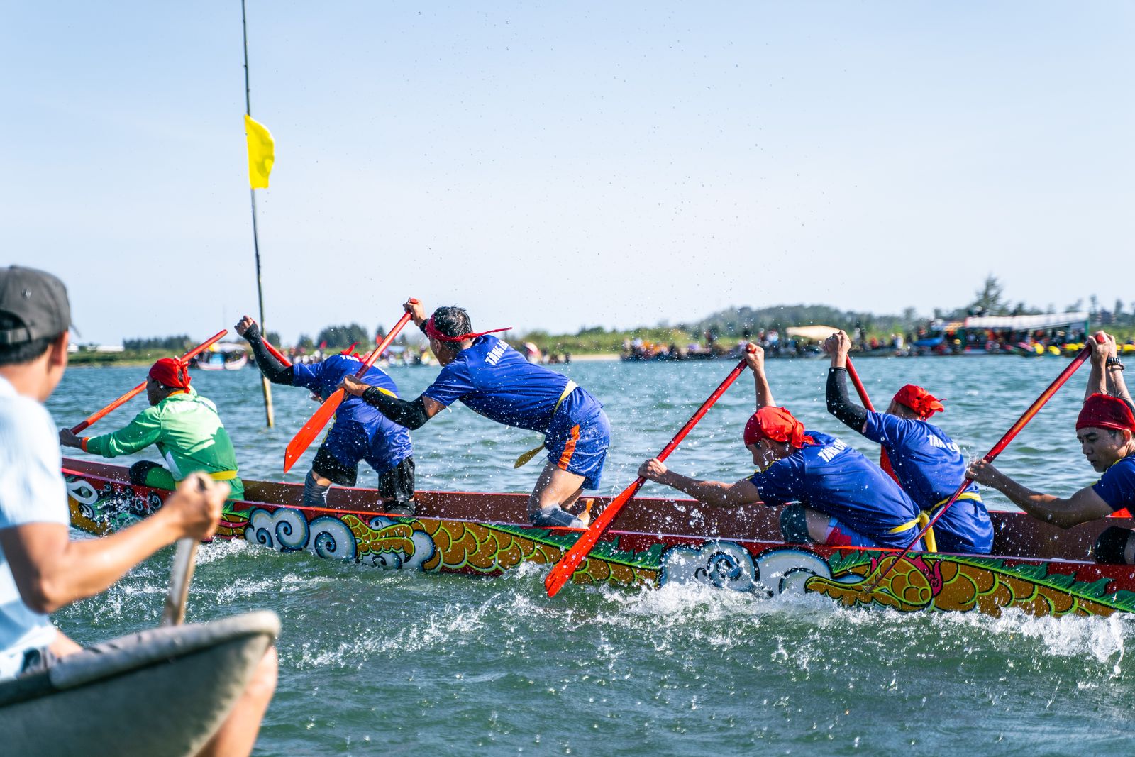A colorful dragon boat race with paddlers in matching uniforms competing on the water in Vietnam