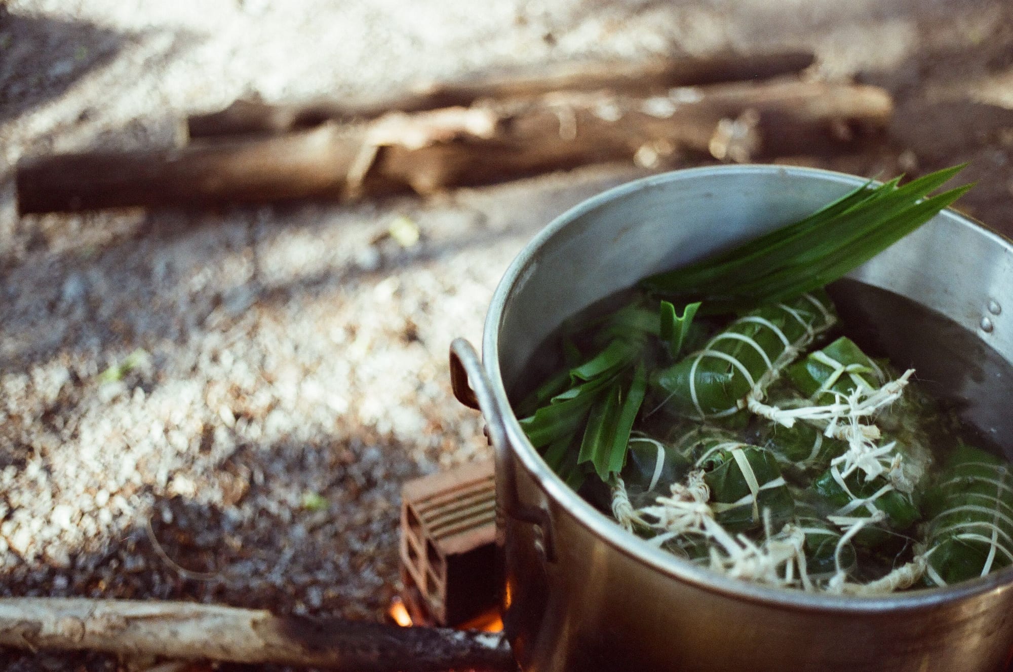 A pot of herbs and broth over an outdoor cooking flame, similar to the sour soups taught in a Phú Quốc cooking class