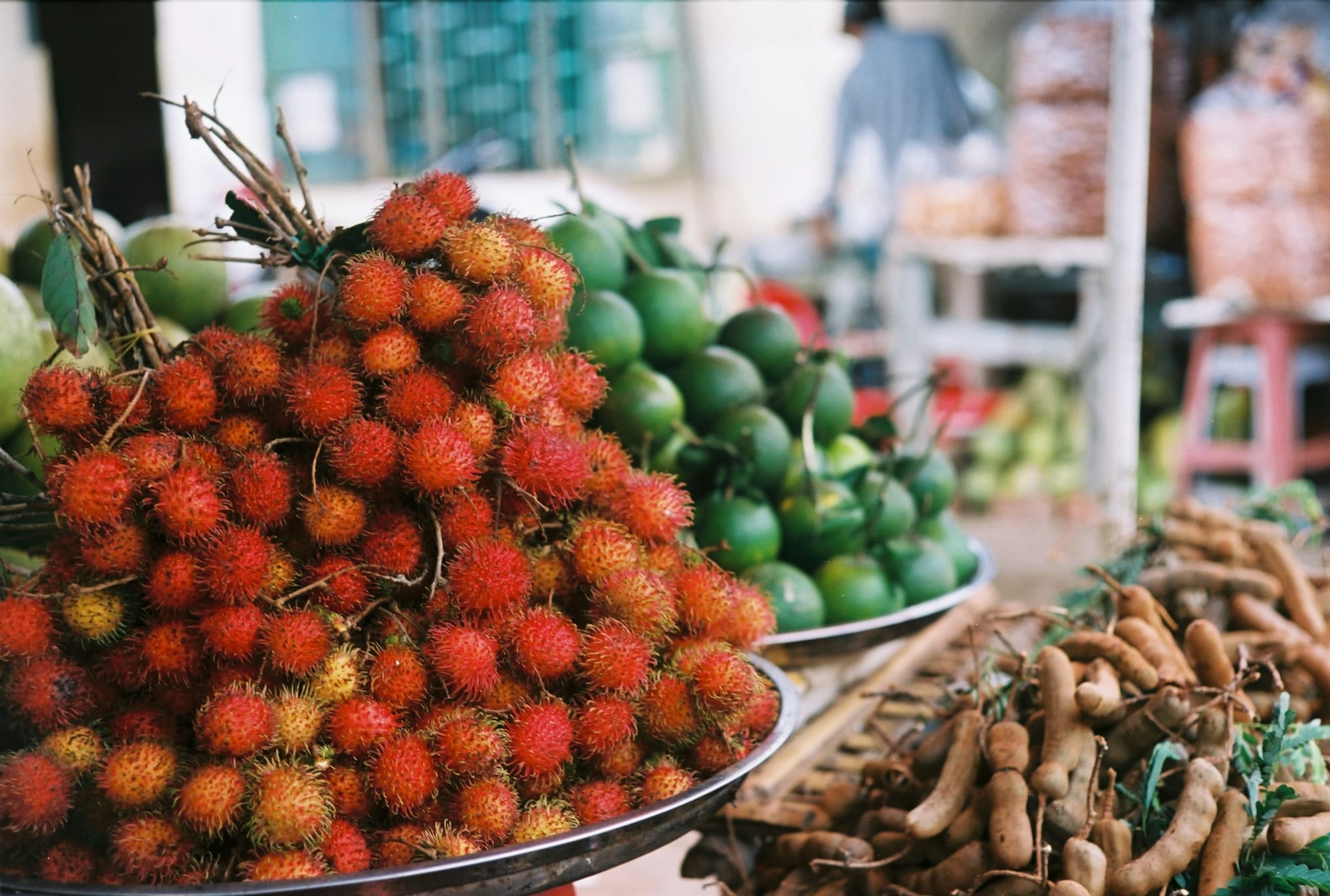 Fresh rambutan and limes piled at a tropical market stall — chôm chôm is one of the key Doan Ngo Festival fruits eaten across southern Vietnam on the fifth month
