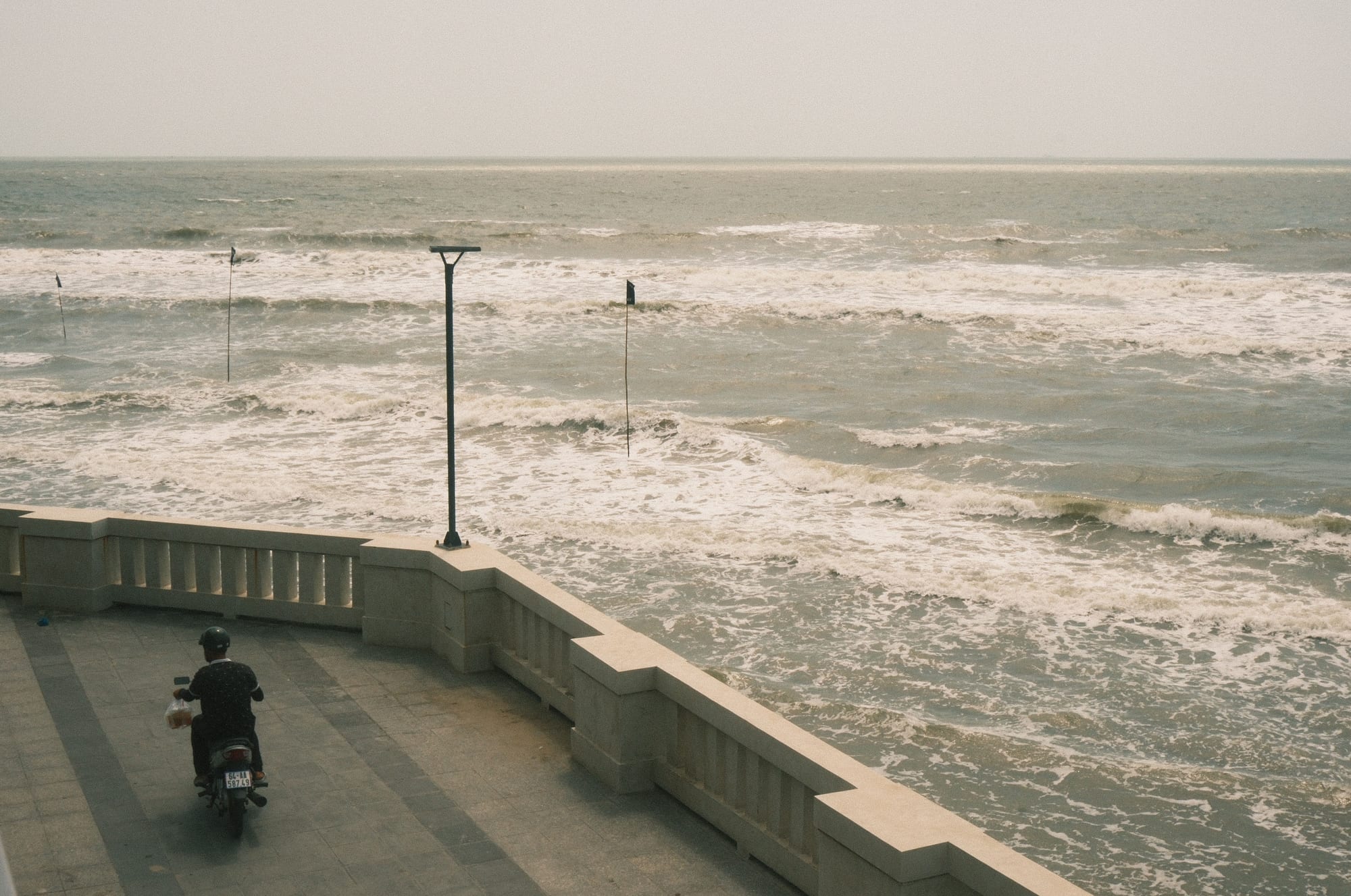 A rider on a scooter following a quiet coastal road, the sea on one side — the kind of riding Phú Quốc is made for